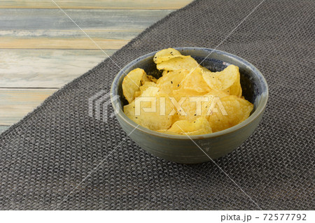 Italian black truffle potato chips in ceramic snack bowl on burlap table runner on table Italian black truffle potato chips in ceramic snack bowl on burlap table runner on table 72577792