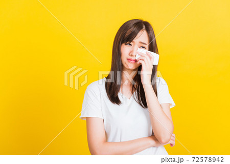 Woman sad she crying wiping tears from eyes with a tissue 72578942