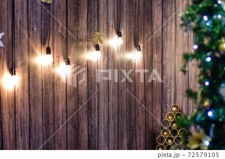 designer Christmas tree with toys on a brown wooden background on which glow incandescent lamps. 72579105
