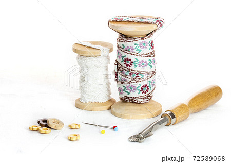 糸巻に巻いたレース2つとマチ針とウッドボタンとルレットとコピースペース 72589068