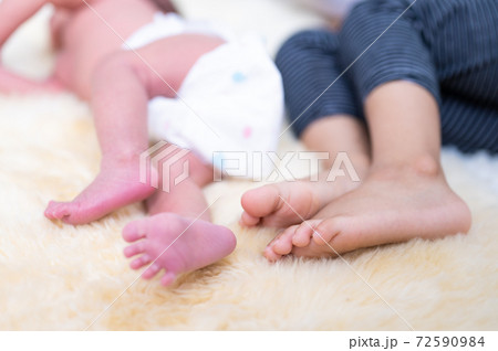 Closeup newborn baby feet and older brother feet sleeping on bed 72590984