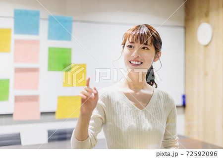 会議室で透明ボードにカラー付箋紙を貼る女性 72592096