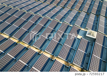 Aerial view of many photo voltaic solar panels mounted of industrial building roof. 72593217
