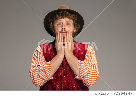 Happy smiling man dressed in traditional Austrian or Bavarian costume gesturing isolated on grey studio background 72594347
