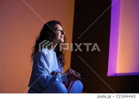 person watches a movie sitting on the couch with a bucket of popcorn person watches a movie sitting on the couch with a bucket of popcorn 72594440