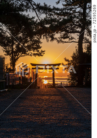 赤い夕日に照らされた鳥居と長く伸びる影 縦構図 の写真素材