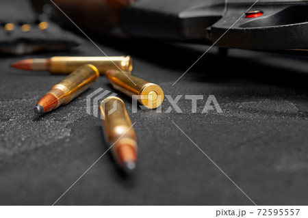 Close up of hunting shotgun and cartridges on dark grey background Close up of hunting shotgun and cartridges on dark grey background 72595557