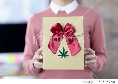Female hands hold box with bow and marijuana logo 72595748