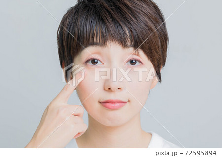 目を指差ししている若い女性 72595894