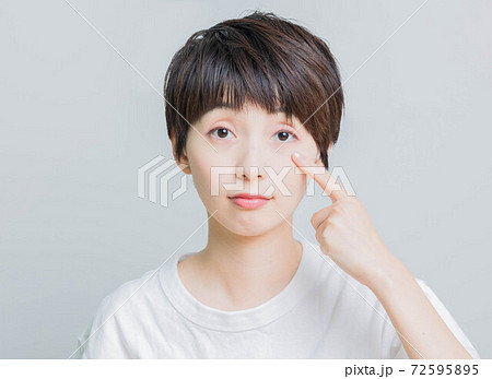 目を指差ししている若い女性 72595895