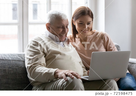 Happy grown daughter and mature dad focused on laptop screen Happy grown daughter and mature dad focused on laptop screen 72598475