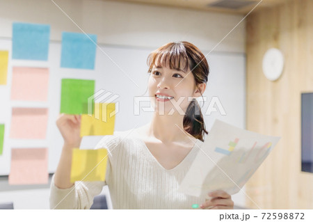 会議室で透明ボードを使って打合せする女性 72598872