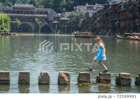 Young Caucasian girl on stepping stones in Fenghuang 72599991