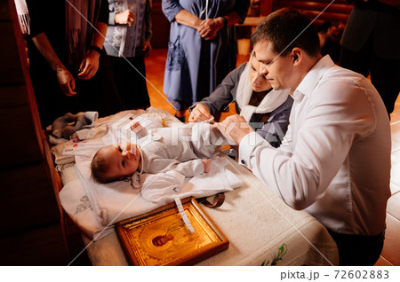 parents dress their child on a table in the Church. the ordinance of baptism. 72602883