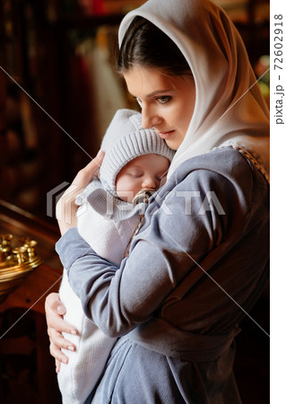 beautiful mom in a headscarf with a small child in her arms in church. beautiful mom in a headscarf with a small child in her arms in church. 72602918