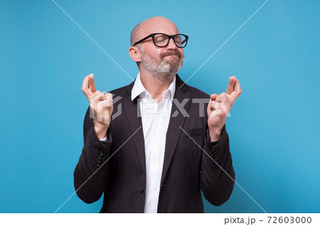 Mature caucasian man with crossed fingers wishing some luck on work. 72603000