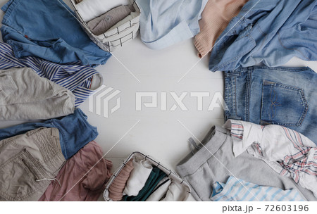 A group of organic cotton clothing laid out on a white table in a circle is ready to be folded into white baskets.The concept of the organization wardrobe. Colors in the Scandinavian style. A group of organic cotton clothing laid out on a white table in a circle is ready to be folded into white baskets.The concept of the organization wardrobe. Colors in the Scandinavian style. 72603196
