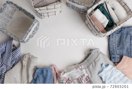 A group of organic cotton clothing set on a white table is ready to be folded into white baskets.The concept of closet organization. Colors in the Scandinavian style. Using the Komari method. 72603201