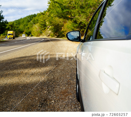side rear-view mirror on a white car on the side of the highway. road travel. side rear-view mirror on a white car on the side of the highway. road travel. 72603257
