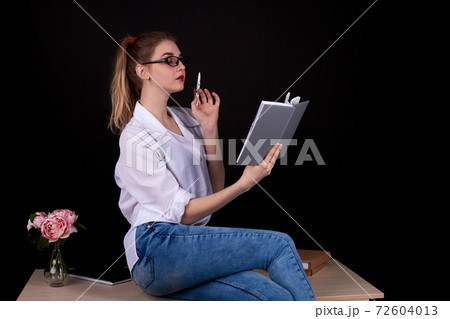 American female teacher is sitting on the table. American female teacher is sitting on the table. 72604013