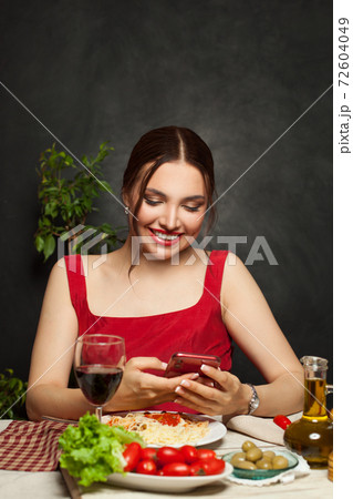 Pretty woman smiling, using phone and eating italian pasta Pretty woman smiling, using phone and eating italian pasta 72604049