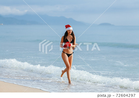 happy girl running with chrismas gift on the beach happy girl running with chrismas gift on the beach 72604297