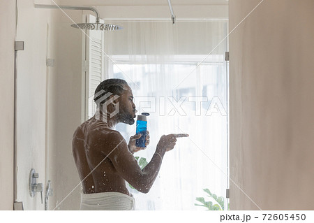 Happy young african ethnicity biracial man entertaining in shower. Happy young african ethnicity biracial man entertaining in shower. 72605450