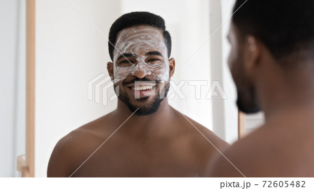 Smiling young 30s african american applying moisturizing mask on face. Smiling young 30s african american applying moisturizing mask on face. 72605482