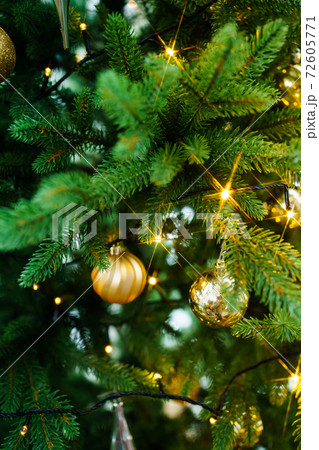 artificial Christmas tree decorated with gold toys and garland bulbs.  72605771