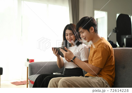 Cheerful happy couple using digital tablet together on sofa at home. Cheerful happy couple using digital tablet together on sofa at home. 72614228
