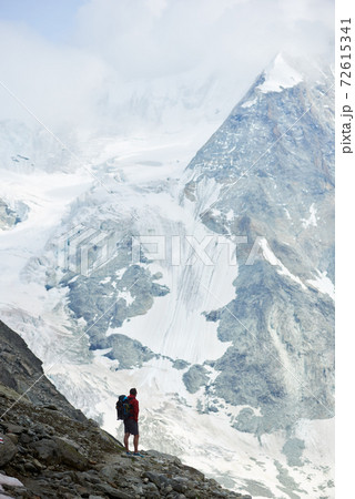 Male tourist climbing snowy rocky cliffs of beautiful Penning Alps in Switzerland Male tourist climbing snowy rocky cliffs of beautiful Penning Alps in Switzerland 72615341