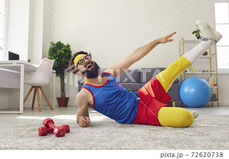 Happy positive funny man working out at home, doing side lying leg lifts and laughing 72620738