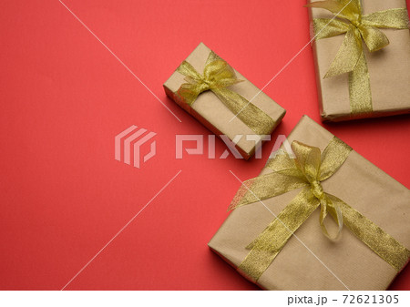box wrapped in brown paper and tied with a golden ribbon with a bow 72621305