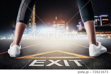 Woman standing on exit signage road for Business exit strategy concept with night city skyline background. Woman standing on exit signage road for Business exit strategy concept with night city skyline background. 72621673