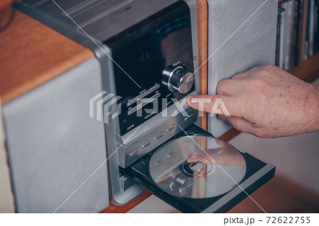 Senior man inserting a CD to the hi-fi station and listening the music Senior man inserting a CD to the hi-fi station and listening the music 72622755
