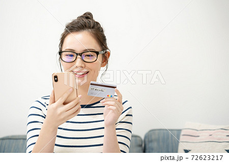 スマートフォンとカードを持つ若い女性 72623217
