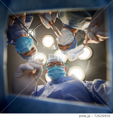 Doctors holding medical instruments and looking at patient. Doctors holding medical instruments and looking at patient. 72626950
