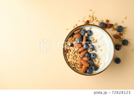 Bowl with tasty granola on beige background 72628123