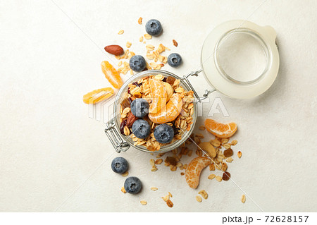 Glass jar with tasty granola on white background 72628157