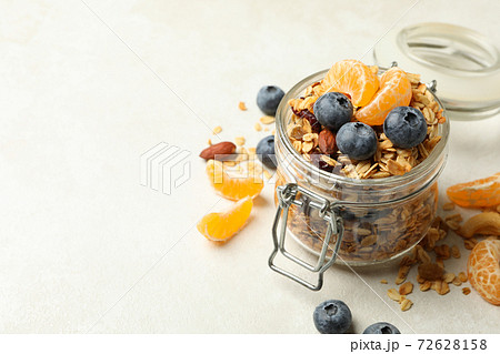 Glass jar with tasty granola on white background Glass jar with tasty granola on white background 72628158