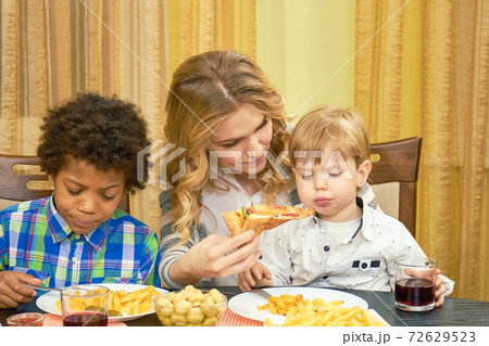 Woman feeding pizza to child. Woman feeding pizza to child. 72629523