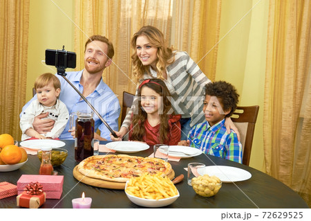 Family taking selfie, dining table. 72629525