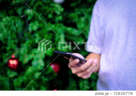Man holding smartphone with christmas tree background, Technology concept. Man holding smartphone with christmas tree background, Technology concept. 72630779