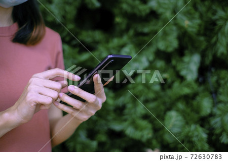 Woman holding smartphone with christmas tree background, Technology concept. 72630783