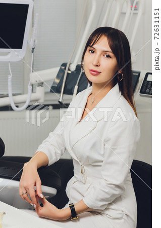 Portrait of attractive smiling female dentist with hands folded. 72631151