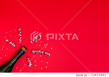 Champagne bottle with confetti on red background 72631842