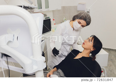 Dentist and patient choosing treatment in a consultation with medical equipment in the background. 72631847