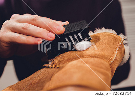 Hands cleaning men's camel suede desert shoe boot with a brush. 72632714