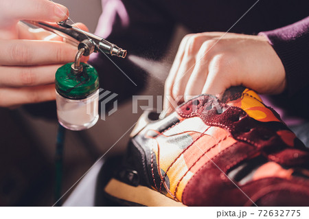 Craft man painting on a pair of shoes. Painting and restoring suede sneakers. 72632775