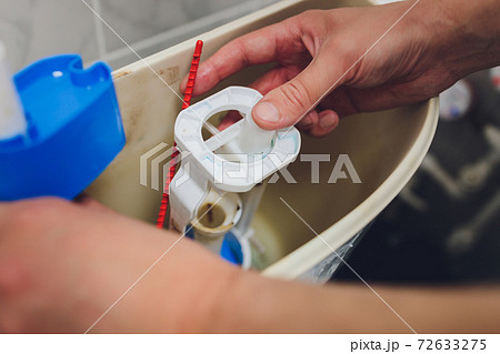 Hand is fixing a toilet cistern at home. Hand is fixing a toilet cistern at home. 72633275
